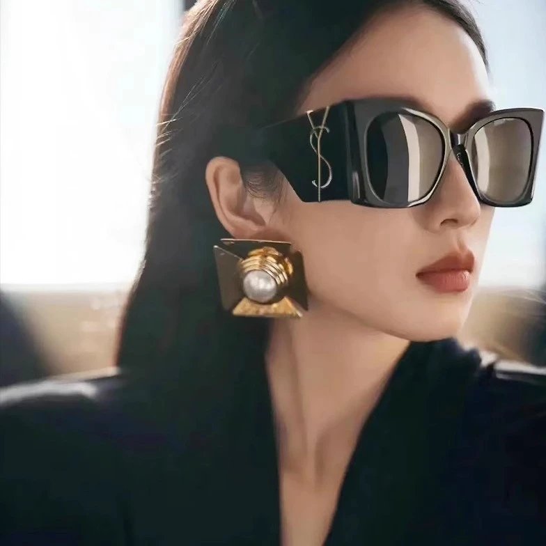 Model wearing square sunglasses and statement earrings
