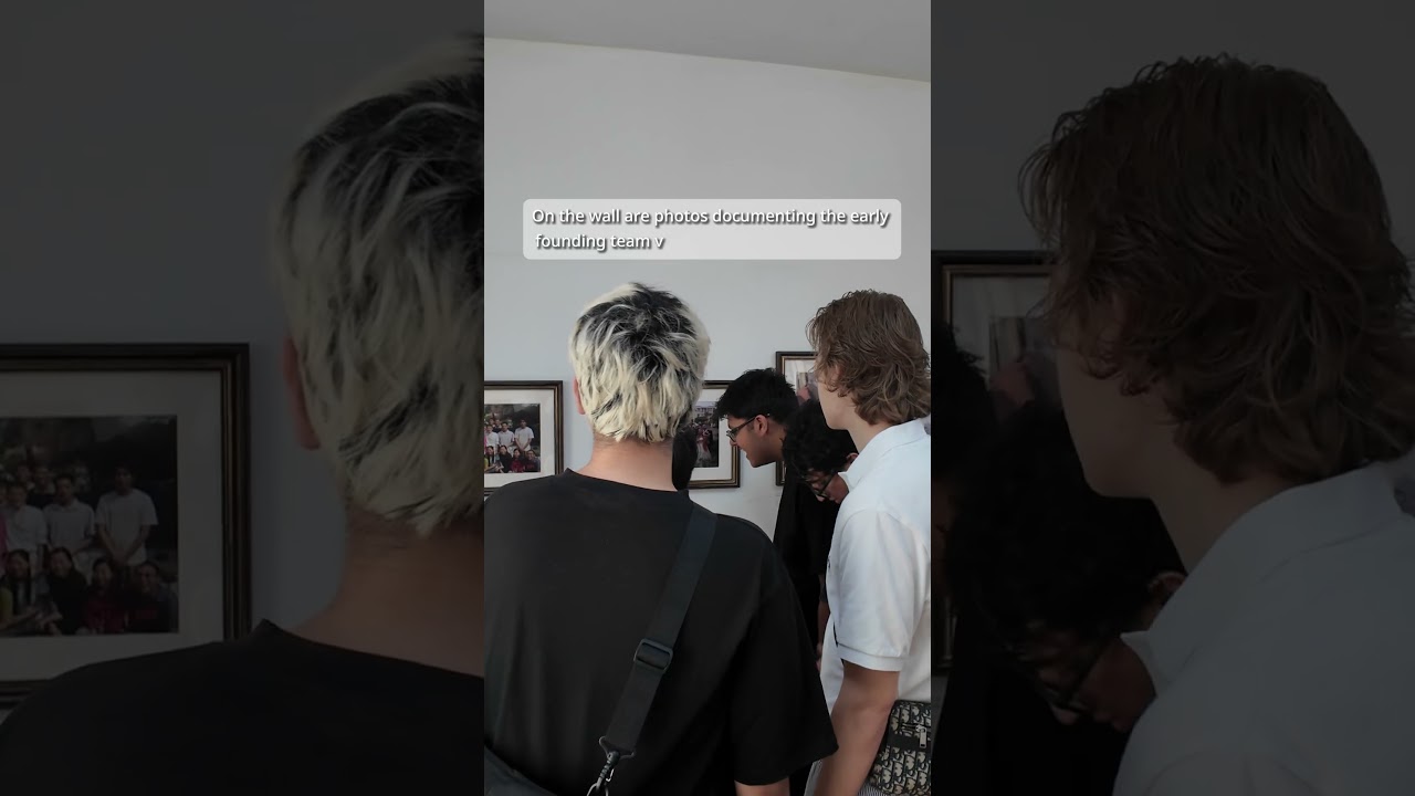 Thumbnail from a Lolobuy creator trip video, showing a visit to the company's office wall of early team photos